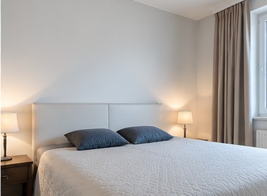 The same bedroom after editing, in soft, natural daylight